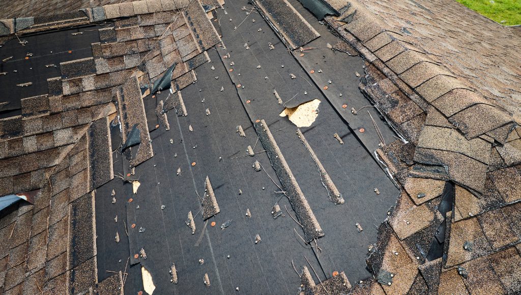 Damaged and missing roof shingles after a storm.