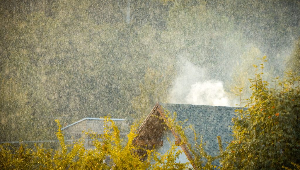 Heavy rain batters an asphalt shingle roof.