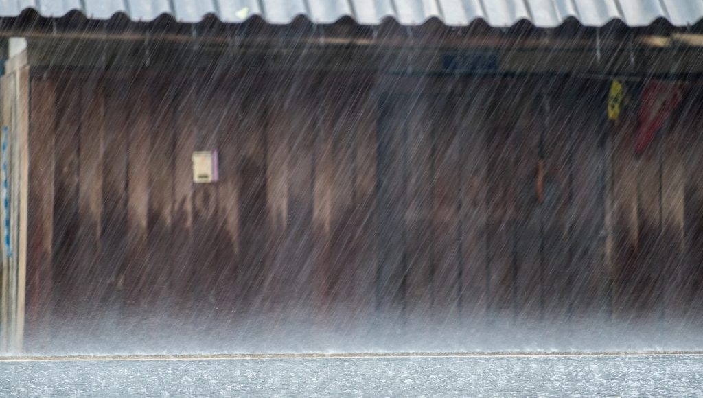 Heavy downpour on a city street, wind gusts causing the rain to fall sideways instead of straight down.