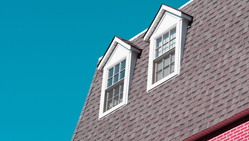 A portion of a south-facing roof with two dormer windows and asphalt shingles.