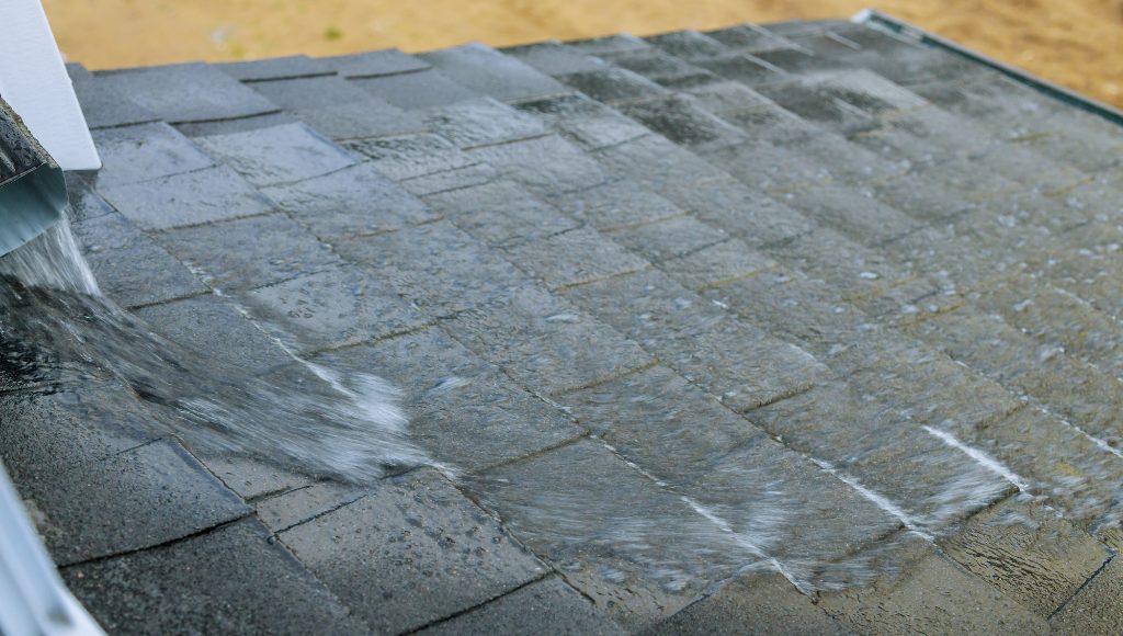 Water flows in a torrent from a gutter onto a lower roof.