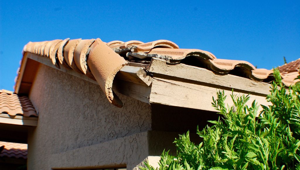 A house with damaged roof tiles on a sunny day.