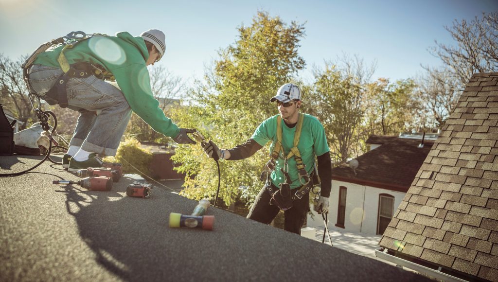 Roofers repair shingles and nail pops on a sunny spring afternoon.