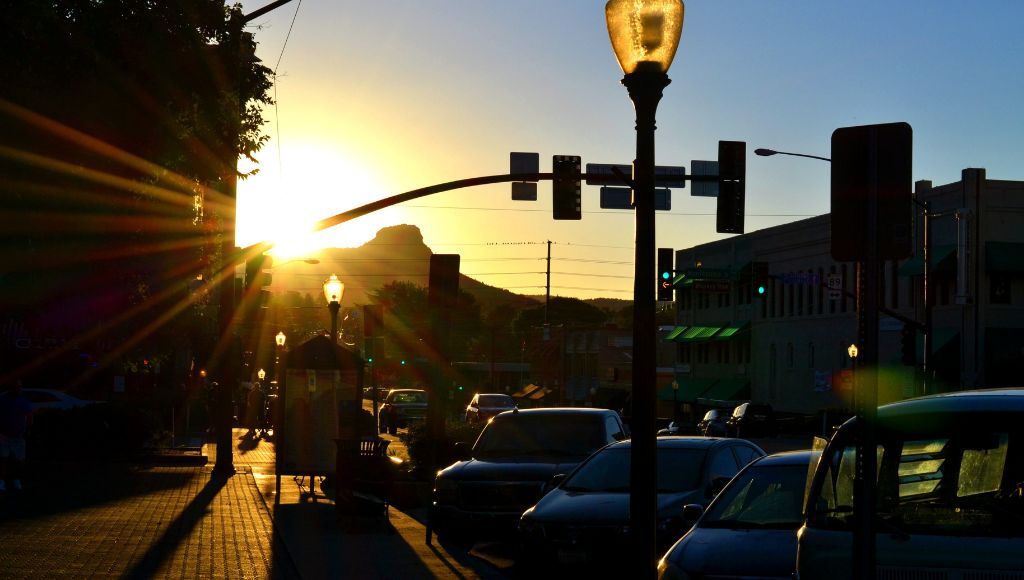 A bright, orange sunset shining through the streets of Prescott. Thumb Butte is visible in the background.