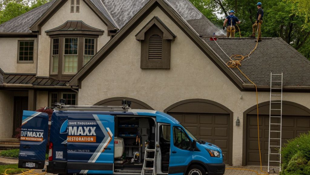 A certified Roof Maxx dealer van parked outside of a residential house in Northern Arizona while two contractors spray an asphalt shingle roof with Roof Maxx.